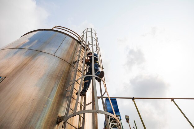 Vista superiore lavoratore maschio si arrampica su la scala ispezione serbatoio inossidabile lavoro in altezza