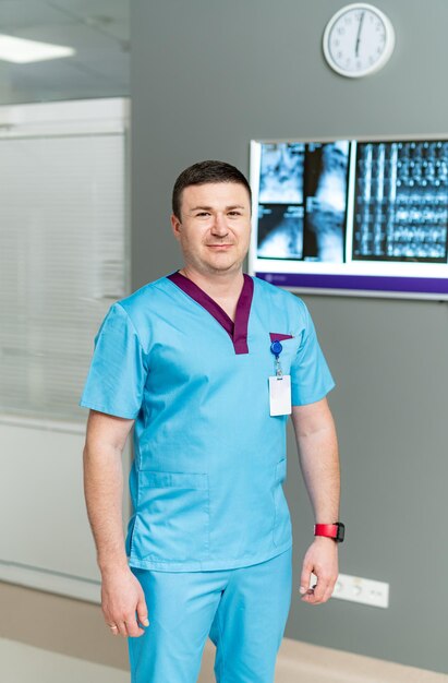 Vista verticale del medico maschio caucasico in piedi al suo gabinetto e guardando la telecamera Medico uomo bello al lavoro in clinica Concetto di assistenza sanitaria