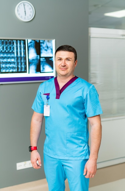 Vista verticale del medico maschio caucasico in piedi al suo gabinetto e guardando la telecamera Medico uomo bello al lavoro in clinica Concetto di assistenza sanitaria