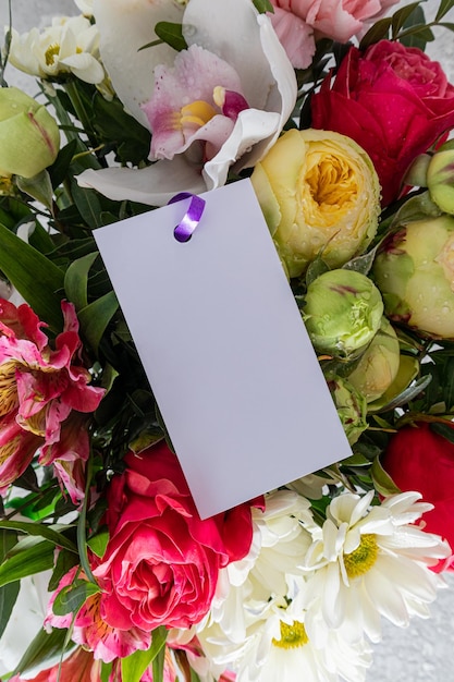 Vista verticale della bella parte luminosa del primo piano del bouquet con una carta bianca vuota per il tuo testo il concetto di un regalo festivo un bouquet