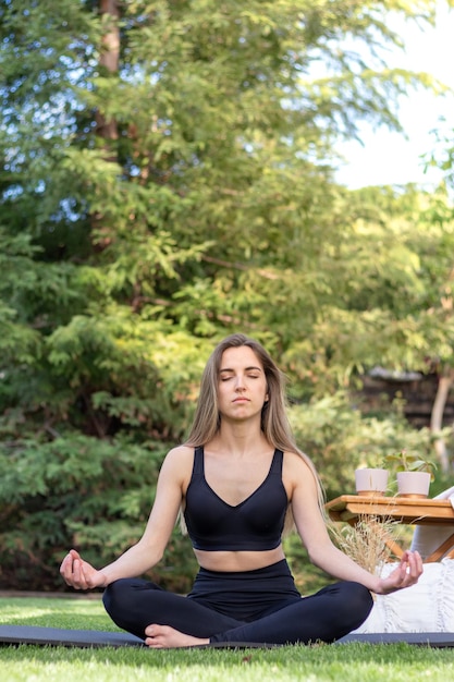 Vista verticale della giovane donna che si gode il suo momento di meditazione in giardino con lo spazio della copia