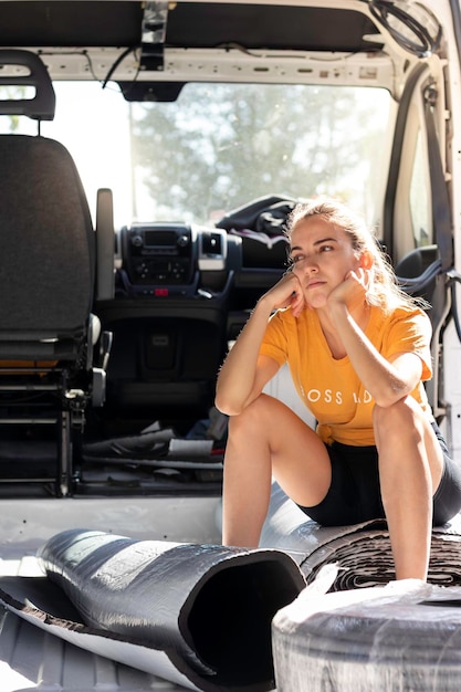 Vista verticale della giovane donna sopraffatta che guarda al camper in costruzione seduto e così via