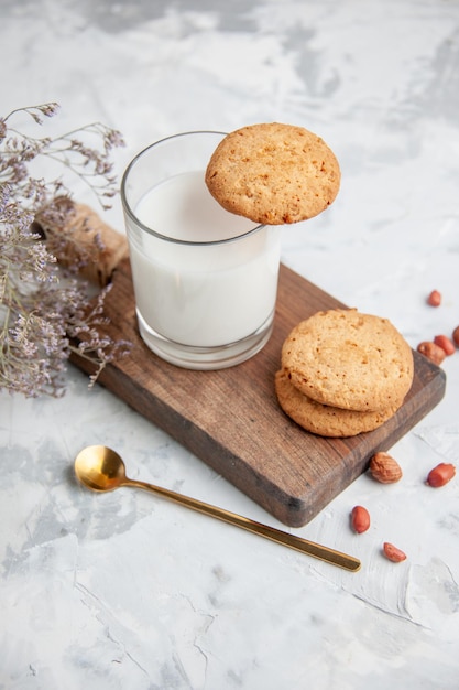 Vista verticale della tazza di vetro riempita di biscotti al latte sul fiore della tavola di legno sul fondo del ghiaccio