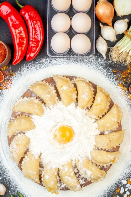 Vista verticale di gnocchi crudi su vassoio di legno marrone intorno a farina e set di alimenti