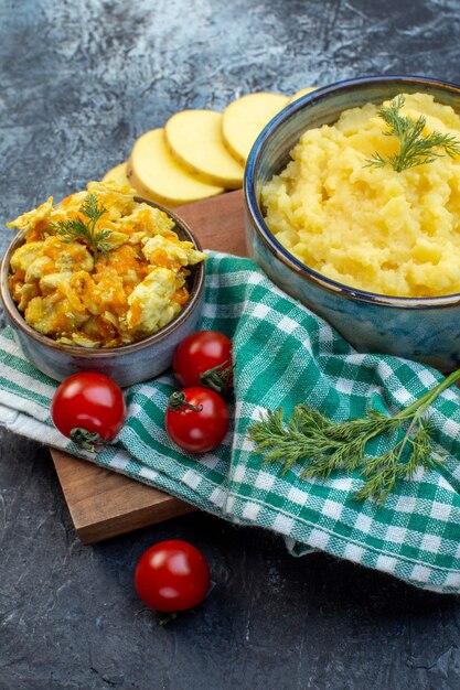 Vista verticale di purè di patate servito con aneto e delizioso piatto di verdure fresche su asciugamano verde spogliato su tavola di legno su sfondo di colore scuro