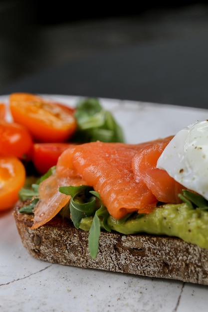 Vista verticale di una bruschetta al salmone crudo con pomodorini sul lato