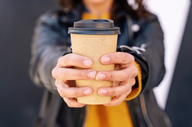 Vista verticale di una donna irriconoscibile che beve una tazza di caffè riciclata all'aperto.