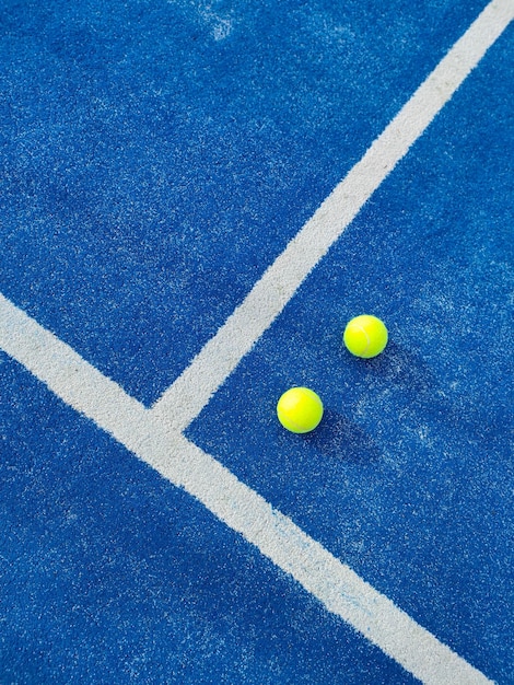 Vista verticale superiore di due palle verdi su un campo da tennis a paddle di erba artificiale blu con linea bianca