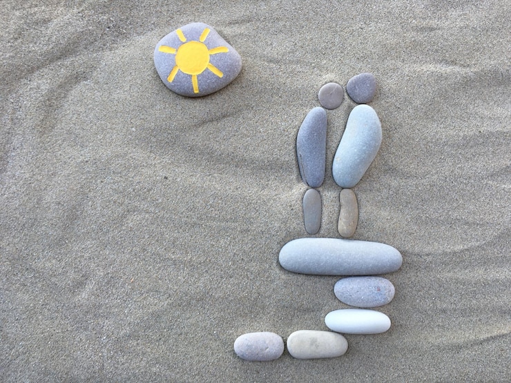 Foto visto direttamente sopra il sole che disegna su ciottoli sulla spiaggia sabbiosa