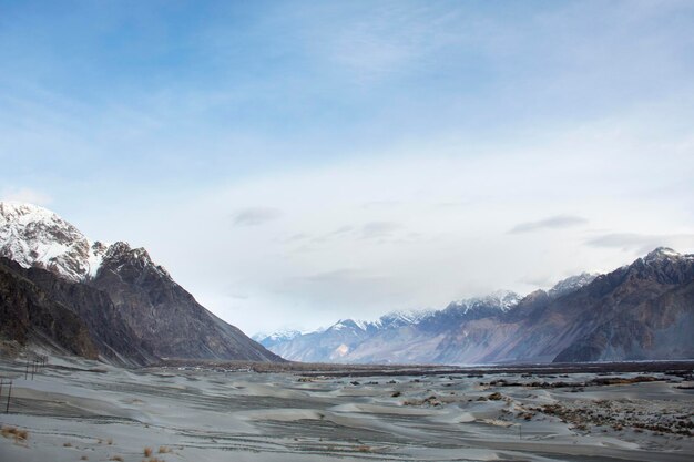 Visualizza il paesaggio con il villaggio di dune di sabbia di Hunder o Hundar nella valle di Nubra Tehsil durante la stagione invernale a Leh Ladakh in Jammu e Kashmir India