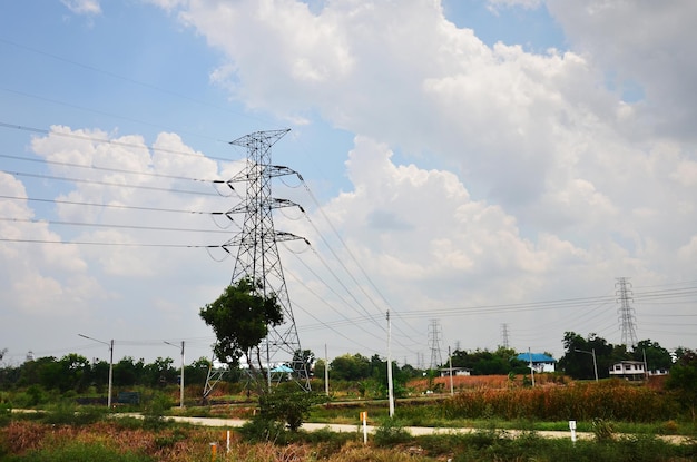 Visualizza la campagna del paesaggio con la colonna del palo di utilità ad alta tensione per la fornitura elettrica locale di supporto in acciaio per le linee elettriche aeree sul percorso della valle del villaggio di campagna rurale a Bangkok in Thailandia