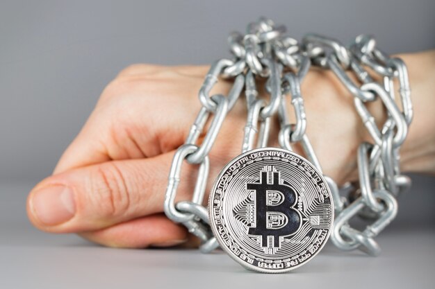 Visualizza su bitcoin. Legato a mano da catena metallica sullo sfondo. Avvicinamento