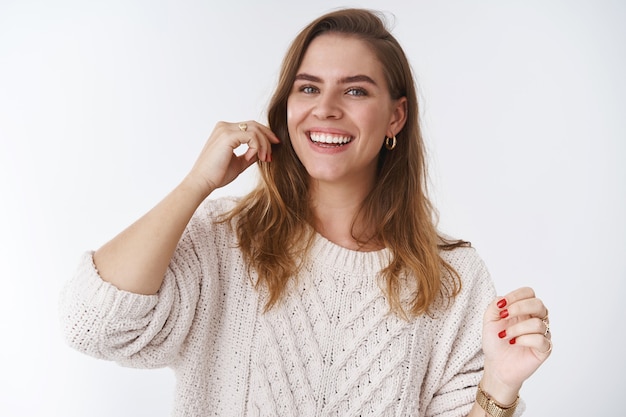 Vita carismatica entusiasta splendida donna caucasica che ride sentendosi sana compiuta gesticolando godendo la vita, buon umore, in piedi gioioso sfondo bianco positivo indossando un maglione sciolto