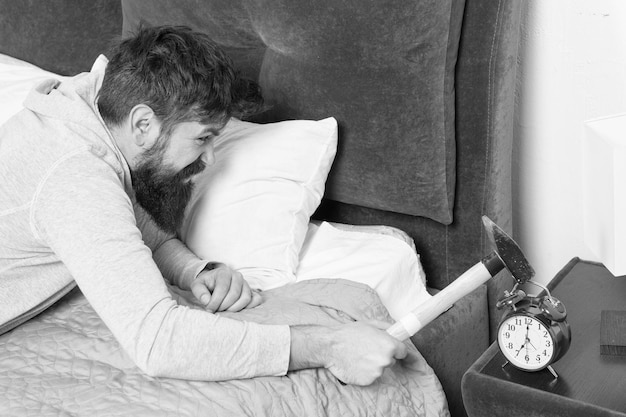 Vita quotidiana Dormire più a lungo Concetto di sonno sano uomo barbuto hipster vuole dormire odiare il rumore della sveglia Ragazzo irritato distruggere orologio fastidioso Uomo sveglio scontento della sveglia che suona