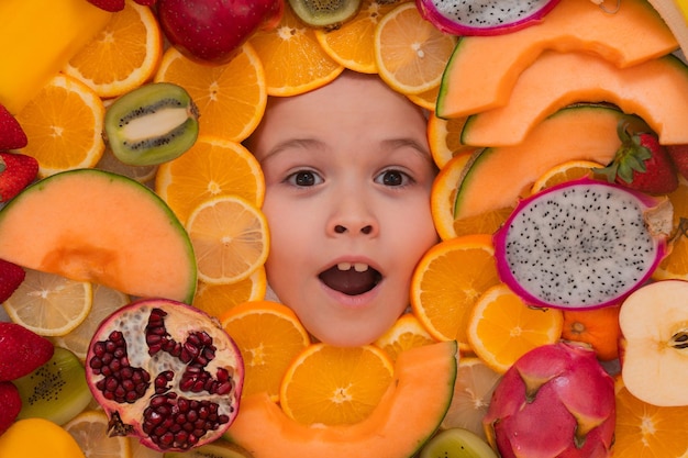 Vitamine da frutta mix di frutta vicino a bambini eccitati affrontano un mix assortito di salute di frutta fresca estiva