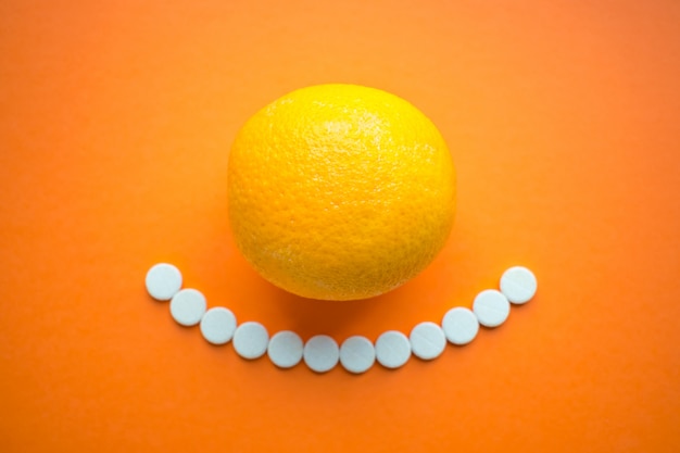 Vitamine estive. frutta arancione e compresse rotonde bianche come un sorriso