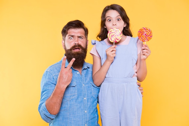 Vittoria a sorpresa Famiglia sorpresa sfondo giallo Padre e figlia celebrano la vittoria Uomo barbuto fanno segno di vittoria Godendo di dolci prelibatezze Vittoria o pace Amore e fiducia Attività divertenti