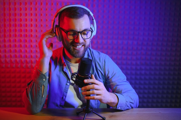 Vlogger che utilizza lo smartphone per filmare podcast in studio blogger con microfono per telefono cellulare e cuffie che filmano video per la carriera di trasmissione sui social media