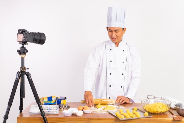 Vlogger di cibo chef maschio utilizzando il mattarello di legno sul tavolo