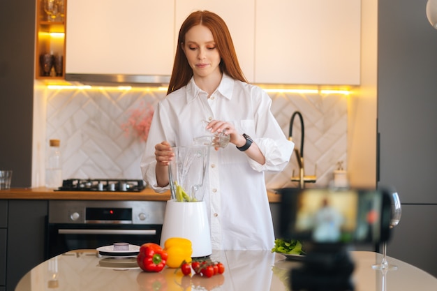 Vlogger di una donna rossa piuttosto attraente che gira un video blog sul cibo sulla produzione di verdure sane