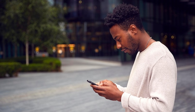 Vlogger maschio o influencer sociale in città che utilizza il telefono cellulare in strada per pubblicare sui social media