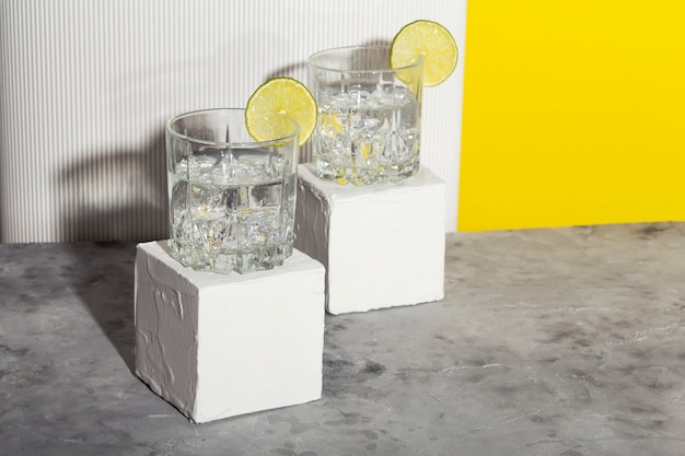 Vodka con ghiaccio e lime in due bicchieri su supporto bianco