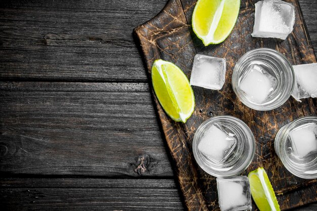 Vodka con ghiaccio su un tagliere con fettine di lime