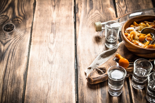 Vodka in stile russo con funghi sott'aceto su fondo di legno