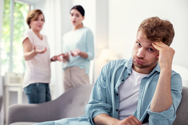 Voglio la pace. Uomo triste triste ascoltando sua moglie e sua madre mentre è stanco di litigi