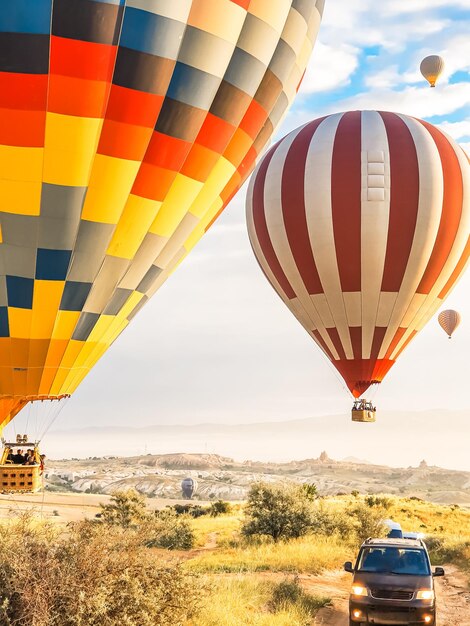 Volando nel cielo molti bellissimi palloncini di colori brillanti in aria in Cappadocia nelle montagne all'alba del sole riempiendo il palloncino con aria calda dal bruciatore grande cestino turisti escursione volo nuvola