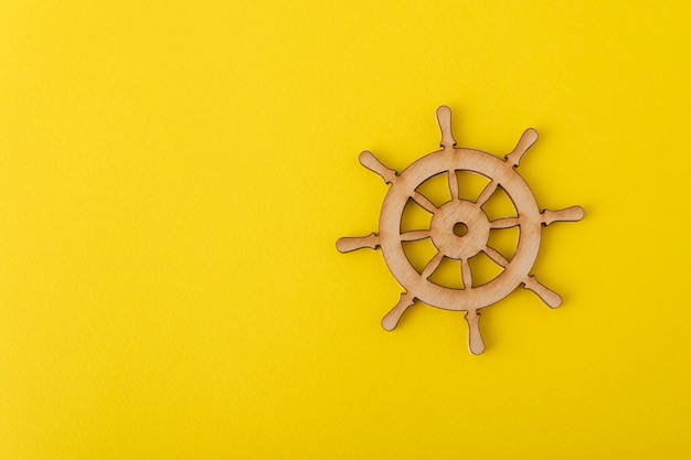 Volante in legno su sfondo giallo. Tema marino. Gestione dello yacht.