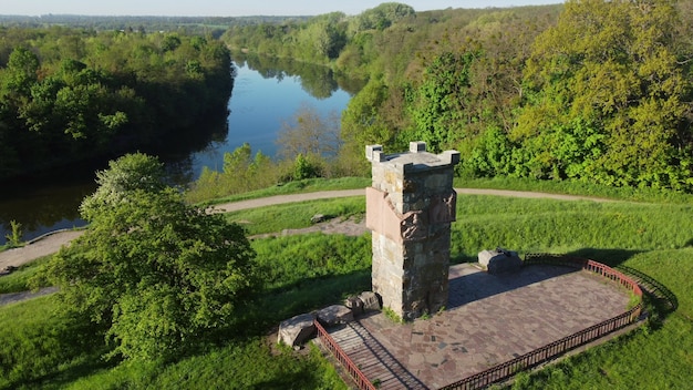 Volo aereo di vista del drone sopra l'erba verde brillante della radura e la vecchia torre in pietra