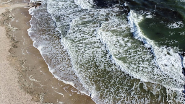 Volo di vista aerea del drone sulle bellissime onde del mare sulla spiaggia di sabbia con schiuma bianca