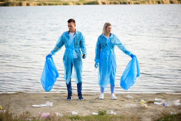 Volontari che raccolgono bottiglie di plastica nel sacco della spazzatura, ecologia, natura, inquinamento, immondizia, cure, volontariato di beneficenza, ambiente della comunità.