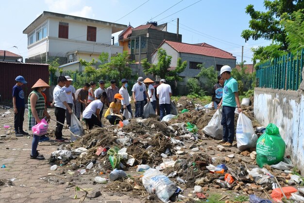 Volontari della comunità giovanile asiatica che usano sacchetti della spazzatura per pulire la natura