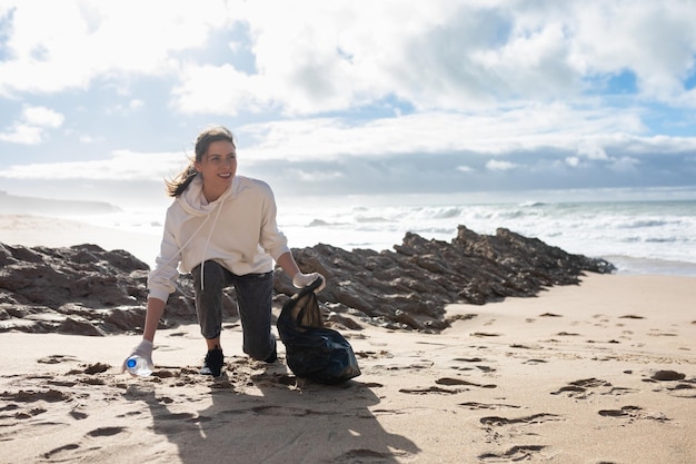 Volontari ecologici femminili che raccolgono rifiuti di plastica sulla spiaggia che raccolgono rifiuti proteggendo lo spazio libero del pianeta