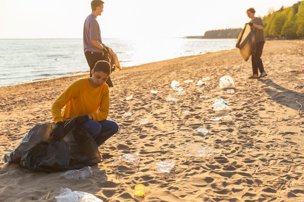 Volontari per la Giornata della Terra attivisti raccolgono la spazzatura pulizia della spiaggia zona costiera donna e uomo mette