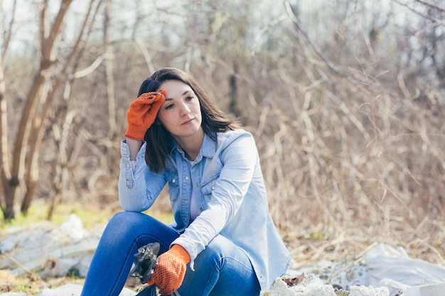 Volontaria femminile stanca di raccogliere plastica dalla foresta e dal parco dalla spazzatura