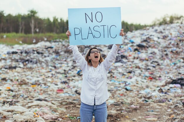 Volontariato femminile picchetti una discarica con un poster senza plastica, l'attivista lotta con l'inquinamento ambientale