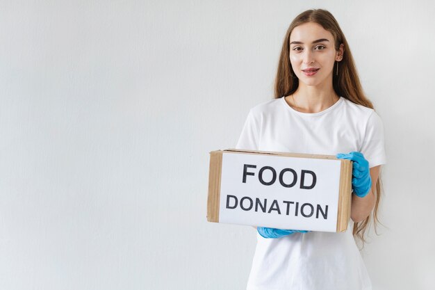 Volontario femminile con guanti che tengono casella di donazione con lo spazio della copia