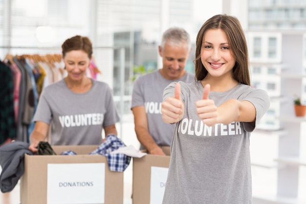 Volontario femminile sorridente che fa i pollici su