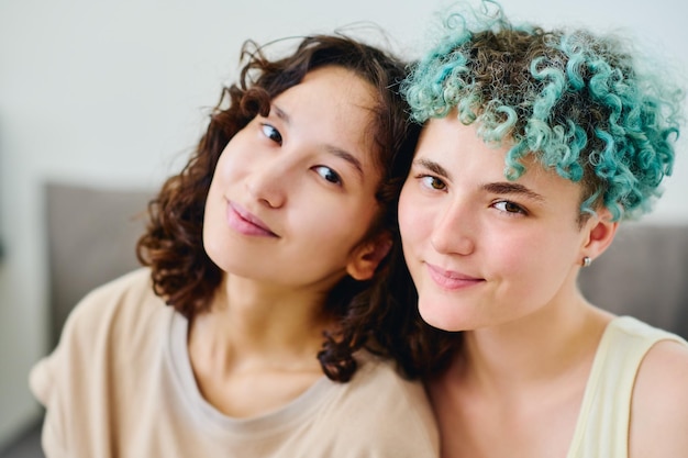 Volti di due giovani amiche interculturali felici in magliette che guardano la macchina fotografica