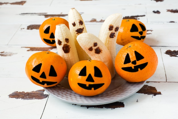 Volti divertenti dipinti su mandarini e banane per Halloween