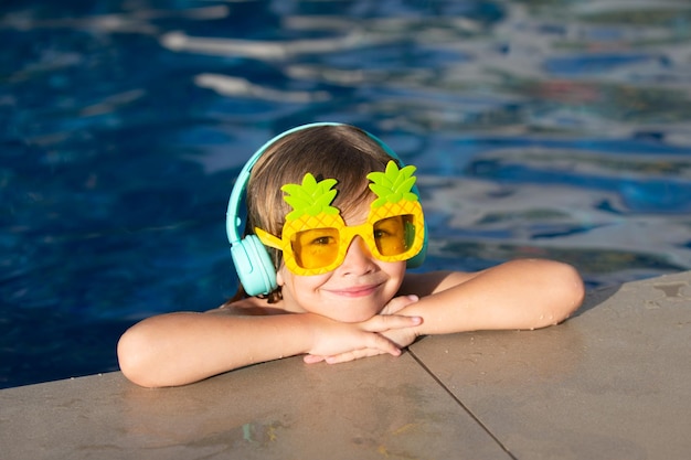 Volto di bambino divertente carino del ragazzino in occhiali da sole divertenti in piscina in una giornata di sole