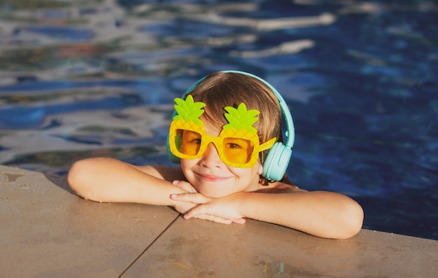 Volto di bambino divertente carino del ragazzino in occhiali da sole divertenti in piscina in una giornata di sole