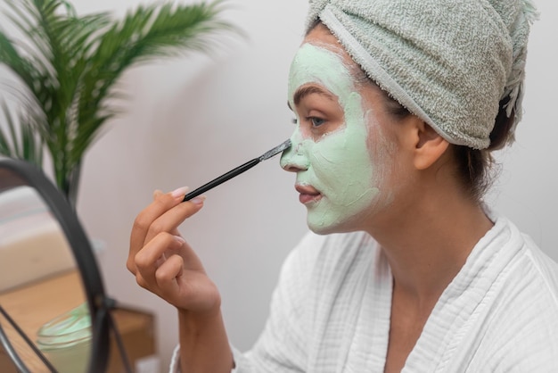 Volto di donna con una maschera idratante che cura la sua pelle salute e bellezza nel comfort di casa