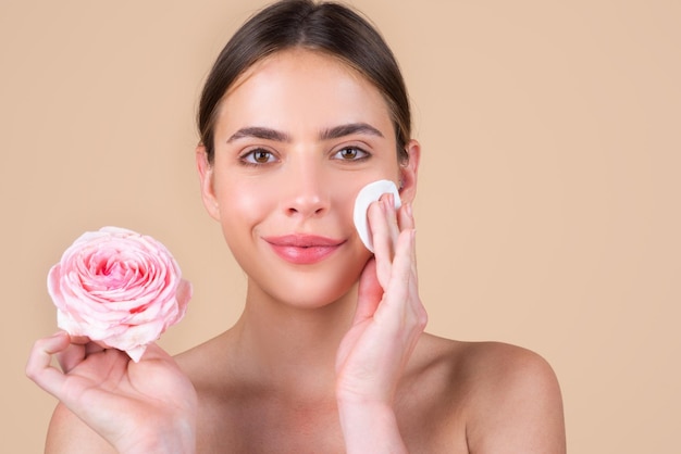 Volto di donna di bellezza con trucco naturale e fiori di rosa, giovane spa modello di bellezza fresca. Bellissimi cosmetici per il benessere femminile. Spa e benessere, concetto di cura della pelle. Trattamento facciale.