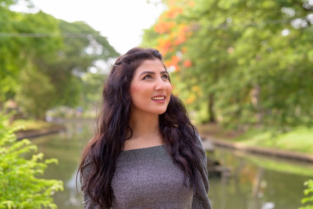 Volto di felice giovane bella donna indiana pensando al parco all'aperto