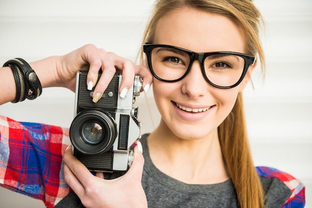 Volto di ragazza alla moda in occhiali da sole con macchina fotografica d'epoca.