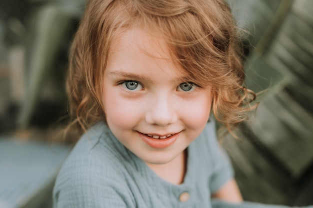 volto di una bambina circondata da foglie tropicali Cosmetici naturali concetto di bellezza per la cura della pelle